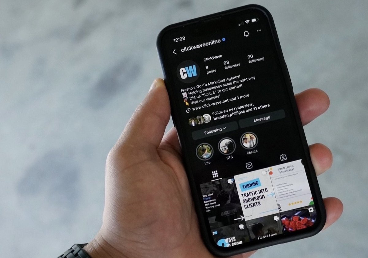 Hand holding a smartphone displaying an Instagram profile page with dark mode interface showing user account information and posts