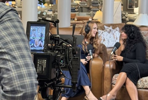 Behind-the-scenes film production with two women being interviewed on camera in a living room setting
